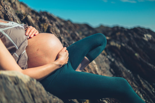 Pregnant woman relaxing on rocks by the sea