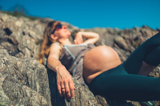 Pregnant woman relaxing on rocks by the sea