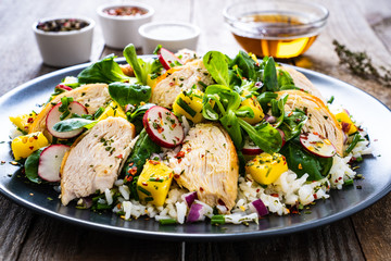 Caesar salad - fried chicken breast, white rice and vegetables on wooden table
