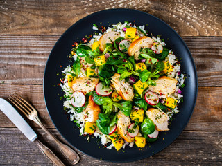 Caesar salad - fried chicken breast, white rice and vegetables on wooden table
