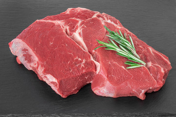 beef meat with rosemary on a black stone board. Fresh piece Raw beef