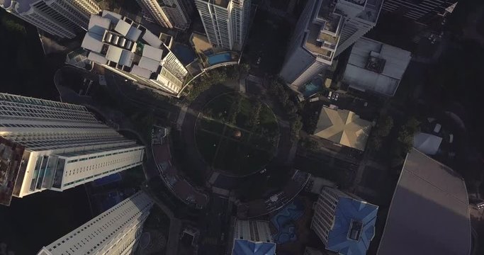 Orbiting descending aerial flight towards roundabout intersection in urban area. Drone, 4K.