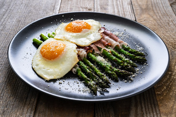 Sunny side up eggs with asparagus and parmesan on wooden background
