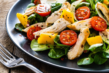 Caesar salad - fried chicken breast and vegetables on wooden table
