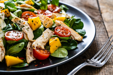 Caesar salad - fried chicken breast and vegetables on wooden table
