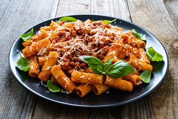 Tortiglioni with tomato sauce, meat and parmesan on wooden background