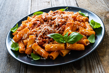 Tortiglioni with tomato sauce, meat and parmesan on wooden background