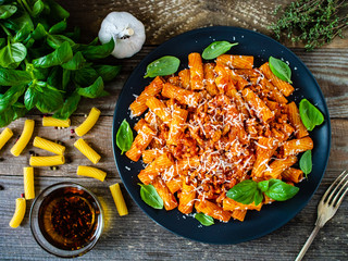 Tortiglioni with tomato sauce, meat and parmesan on wooden background