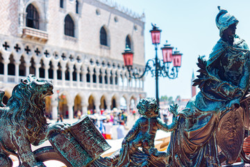 Sculptural composition on the gate that opens the entrance to the campanile of St. Mark with the Doge's Palace in the background.