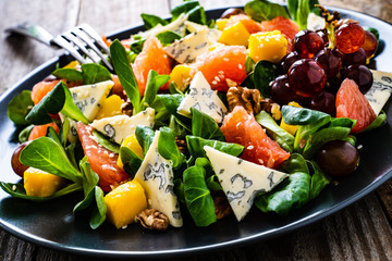 Fresh salad - blue cheese, fruit and vegetables on wooden table
