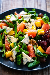 Fresh salad - blue cheese, fruit and vegetables on wooden table
