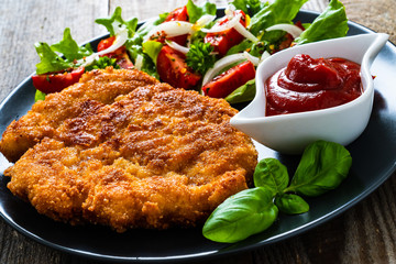 Pork chop with boiled potatoes and vegetable salad on wooden background