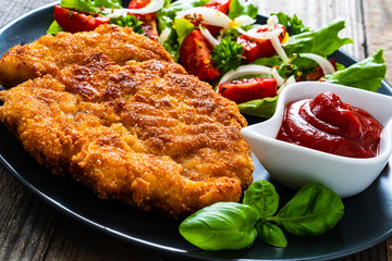 Pork chop with boiled potatoes and vegetable salad on wooden background
