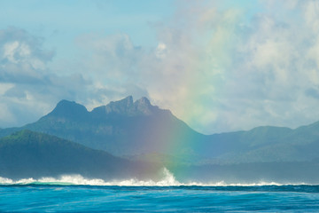 A huge rainbow against the backdrop of picturesque mountains, waves and ocean. Mauritius Island, Indian Ocean
