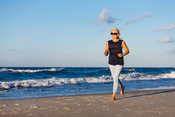 Middle-aged woman running on beach