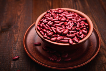Close up of a bowl of raw red beans on a wooden table