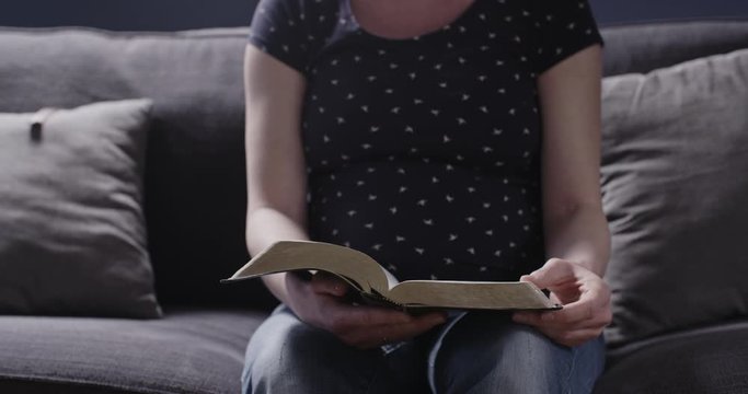 An expectant mother, a pregnant woman, reading the Bible at home.