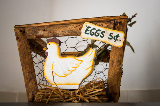An old wooden, straw and wicker basket inside the kitchen of a house and the detail of a hen. A basket that should contain 54 eggs.
