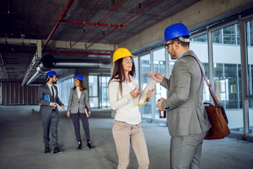 Architects standing inside of building in construction process and talking about important project.