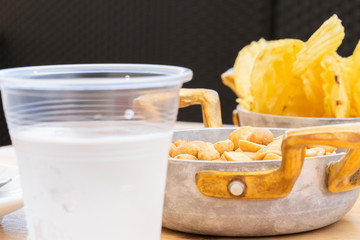 Morning aperitif at the bar. Salted peanuts and fried chips served on a metal bowl on a June morning.