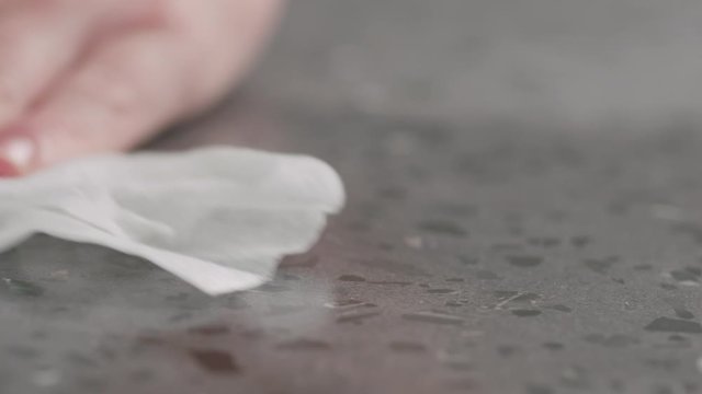 Slow motion spraying sanitizer on concrete countertop surface and wipe it macro shot