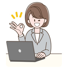 パソコンの前でOKサインをするスーツの女性