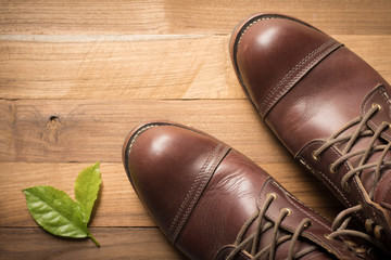 ฺBrown leather shoes with vintage camera on a wooden floor.Brown vintage leather boots aligned selective focus.Men leather shoes 