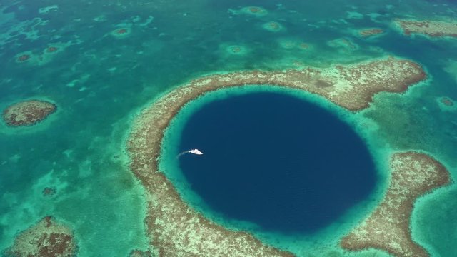 Aerial view of yacht moving on marine sinkhole during sunny day, scenic view of seascape - Great Blue Hole, Belize