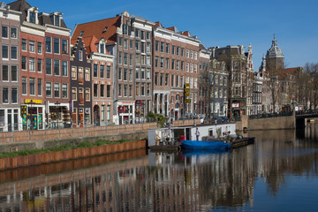 Naklejka premium April 2020 - Amsterdam, The Netherlands - Romantic view of Amsterdam city centre canals and boats on Spring time 