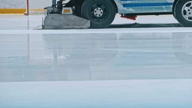 Zamboni resurfacing an indoor skating rink. Slow Motion. Ice resurfacer cleaning ice, machine cleaning and polishing smooth icerink. Ice harvester or restores ice.