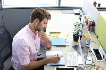 Fototapeta premium Portrait of young man sitting at his desk in the office.