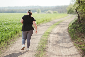 Overweight young woman jogging outdoors. Weight loss, sports, healthy lifestyle