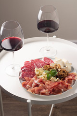 red wine and cheese and meat snacks on the table

