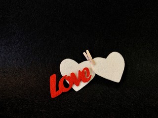 Two hearts are clamped by a clothespin on a dark background. Sign: love and fidelity for two....