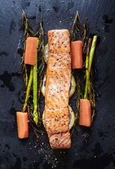 Grilled Salmon baked fillet steak, with lemon, Asparagus, Rosemary and Carrot on black stone plate
