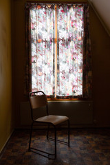 lonely chair by the window with curtains drawn too