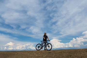 Fototapeta na wymiar Sports brutal bearded guy on a modern mountain bike. A cyclist in a salt deserted place by the lake.