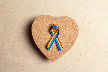 LGBT rainbow ribbon and cork heart on a brown cardboard background. Pride tape symbol. Gender equality concept.