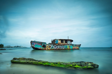 Long exposure shot of an abandoned boat close to shore shot at San Andres, Colombia. 