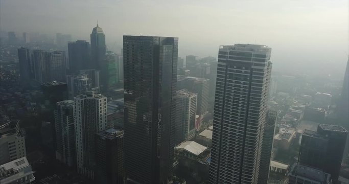 Tilt up aerial flight of urban area revealing high rise building. Drone, 4K.