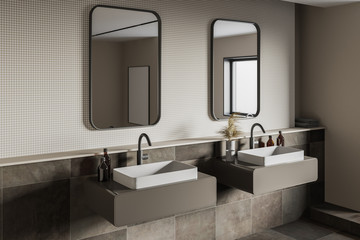 Beige and tiled bathroom corner with double sink