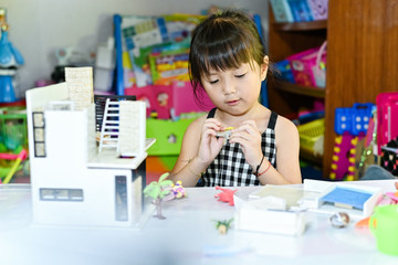 Asian little girl children playing at toy and leaning to enjoy the saturday morning at toy corner home building