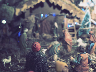 Christmas holidays at home. A christmas nativity scene with lights and small wooden statues illuminates the living room during the evening.