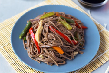 Soba noodles with chicken and vegetables on a plate, japanese food, view from above
