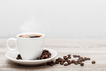 Coffee cup with a white saucer and coffee beans on a wooden table with space background