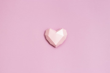 Pink polygonal paper heart shape on pink paper. Holiday background with copy space for Valentines Day. Love concept. Plain colored. Monochrome image. Minimal style.