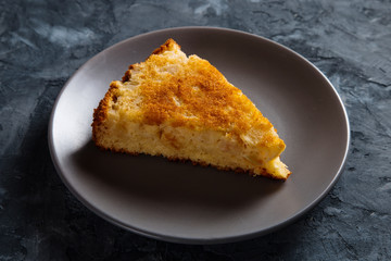 A piece of apple pie on a gray plate, against a concrete background.