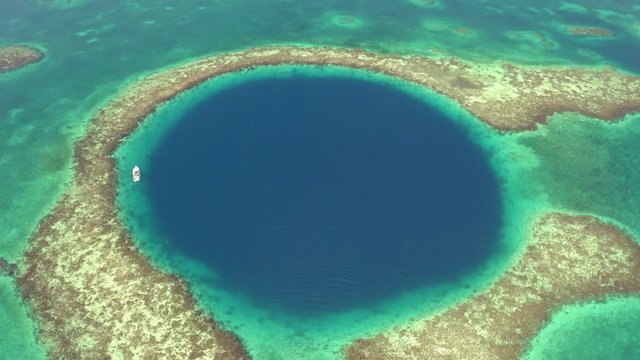 Aerial: Yacht in marine sinkhole on sunny day, scenic view of seascape - Great Blue Hole, Belize