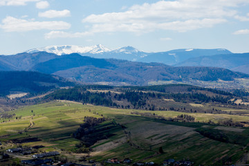 Obraz premium View of the Carpathian Mountains landscape in cloudy summer day. Mountain peaks, forests, fields and meadows, beautiful natural landscape