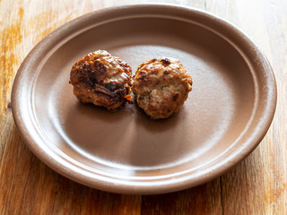 two fried russian Kotleta (breaded meat balls) on ceramic plate on old wooden table at home kitchen